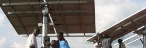 Six people work to install solar panels in Rwanda to power health clinics