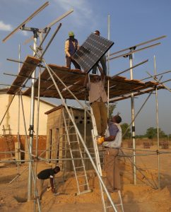Five men install solar panels from the Solar Electric Light Fund (SELF) in a rural village