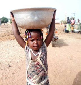 A child holds a basin of clean water in Benin