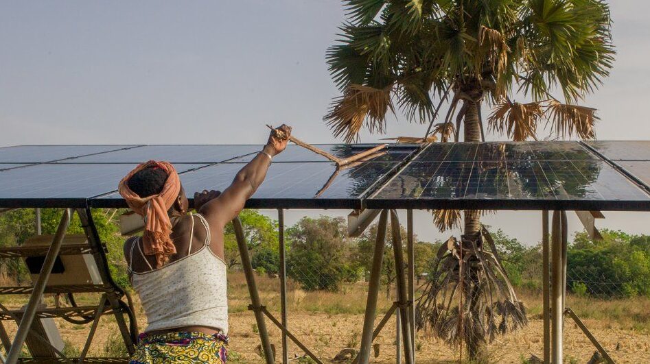 A woman cleans a solar panel, which is a promising technology for tackling climate change and poverty in Africa
