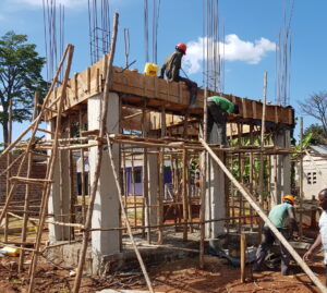 A construction team builds a structure for a solar-powered water tank as part of a sustainable development project in Uganda