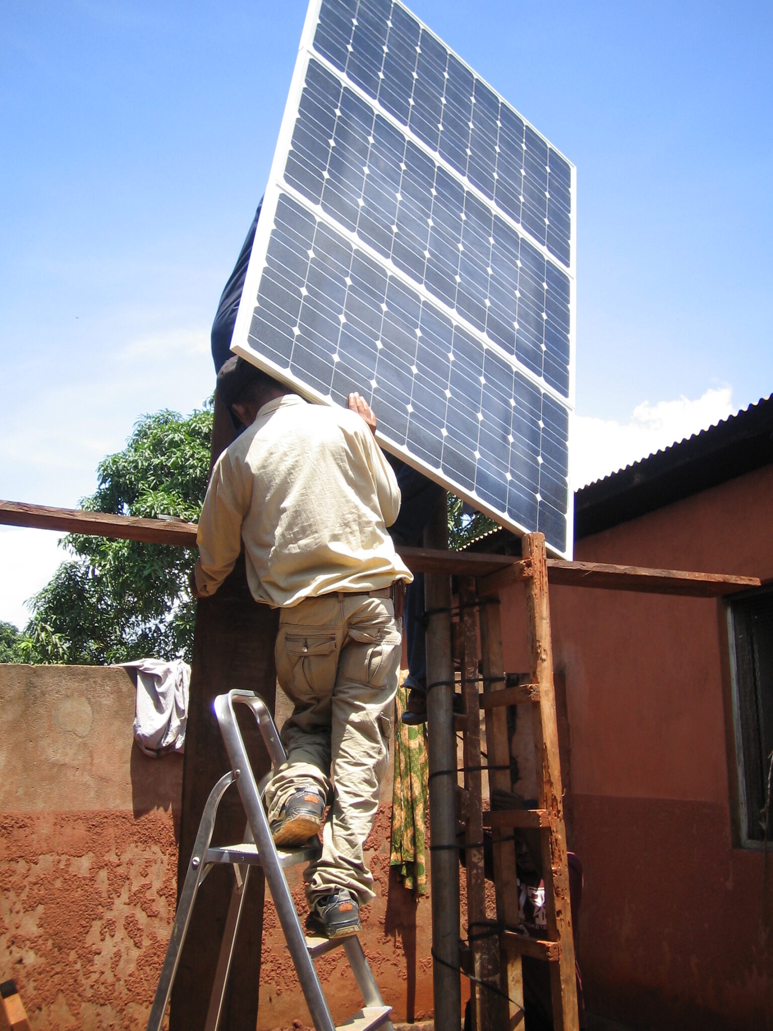 Two men set up solar panels on a rooftop as part of a sustainable development project