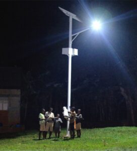 Children in Uganda read under a streetlight powered by solar energy
