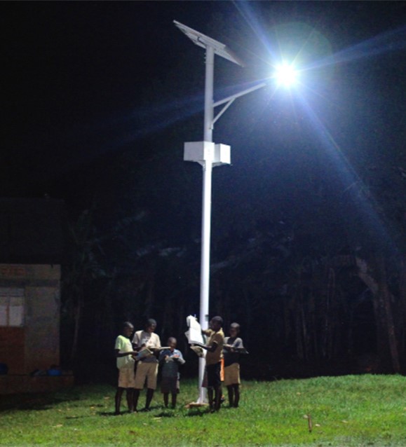 Children stand below a solar streetlight, which is one application of solar energy for sustainable development